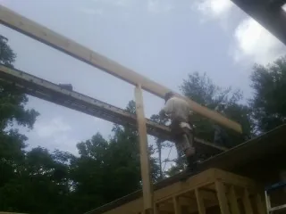 Carpenter setting a ridge beam over a new addition frame — Ice Dam Removal by Roofing Brothers in Lynn