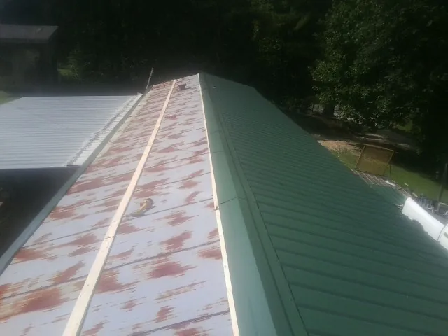 Old rusted panels beside newly installed green metal roofing — Wind Damage Roof Repair by Roofing Brothers in Lynn