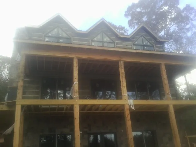 Dormers and porch framing on a large log home under construction — Roof Coating work by our crew in Lynn
